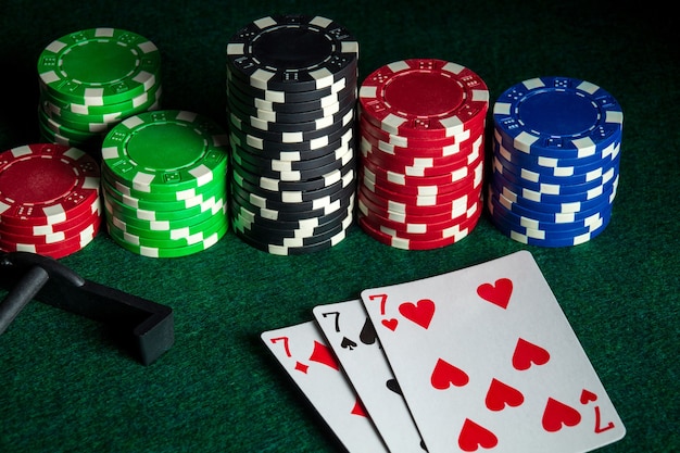 Ảnh cao cấp | Thẻ bài poker với sự kết hợp ba loại hoặc bộ trong sòng bạc. Chip và cào trên bàn xanh